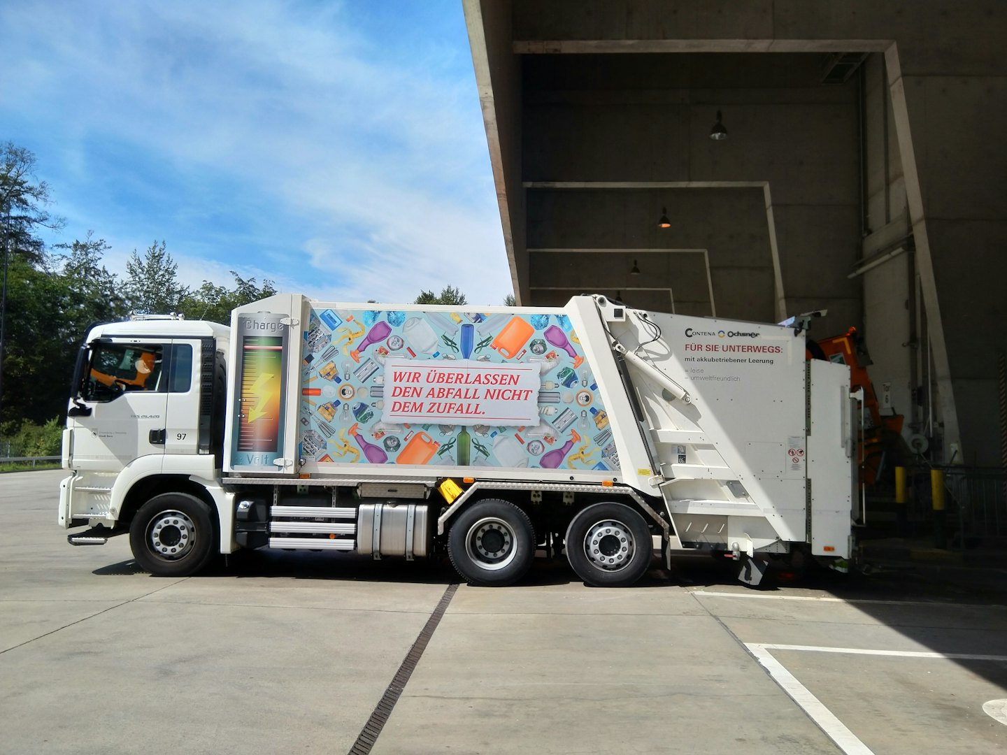 White recycling truck parked on concrete lot.