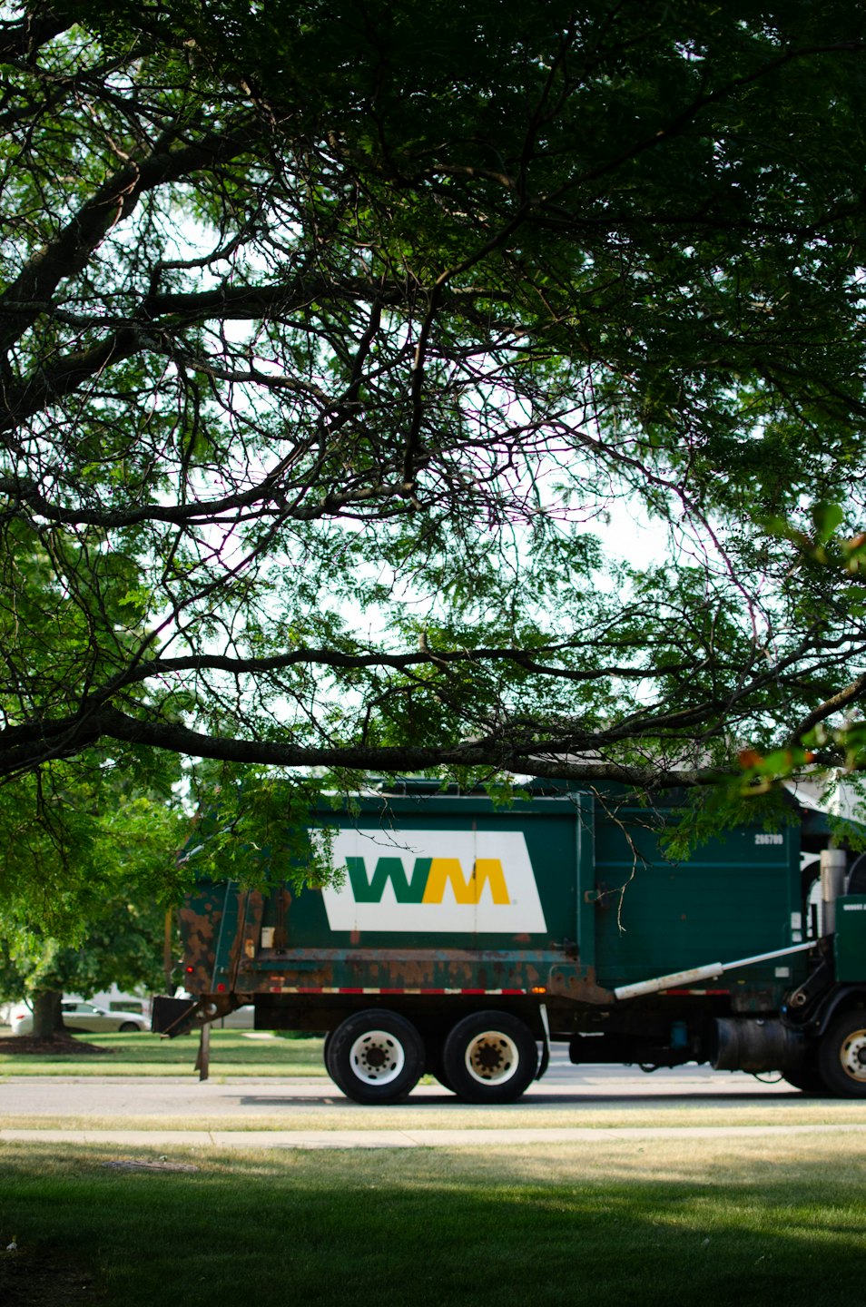 Waste Management garbage truck drives down a paved road.