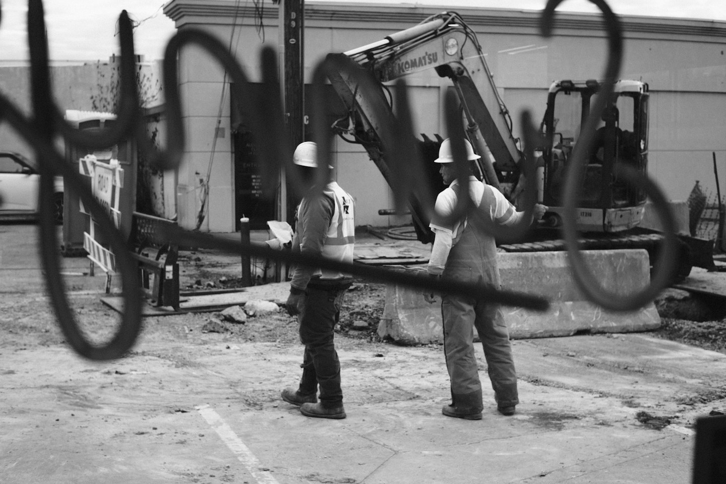 Construction workers review documents near an excavator.