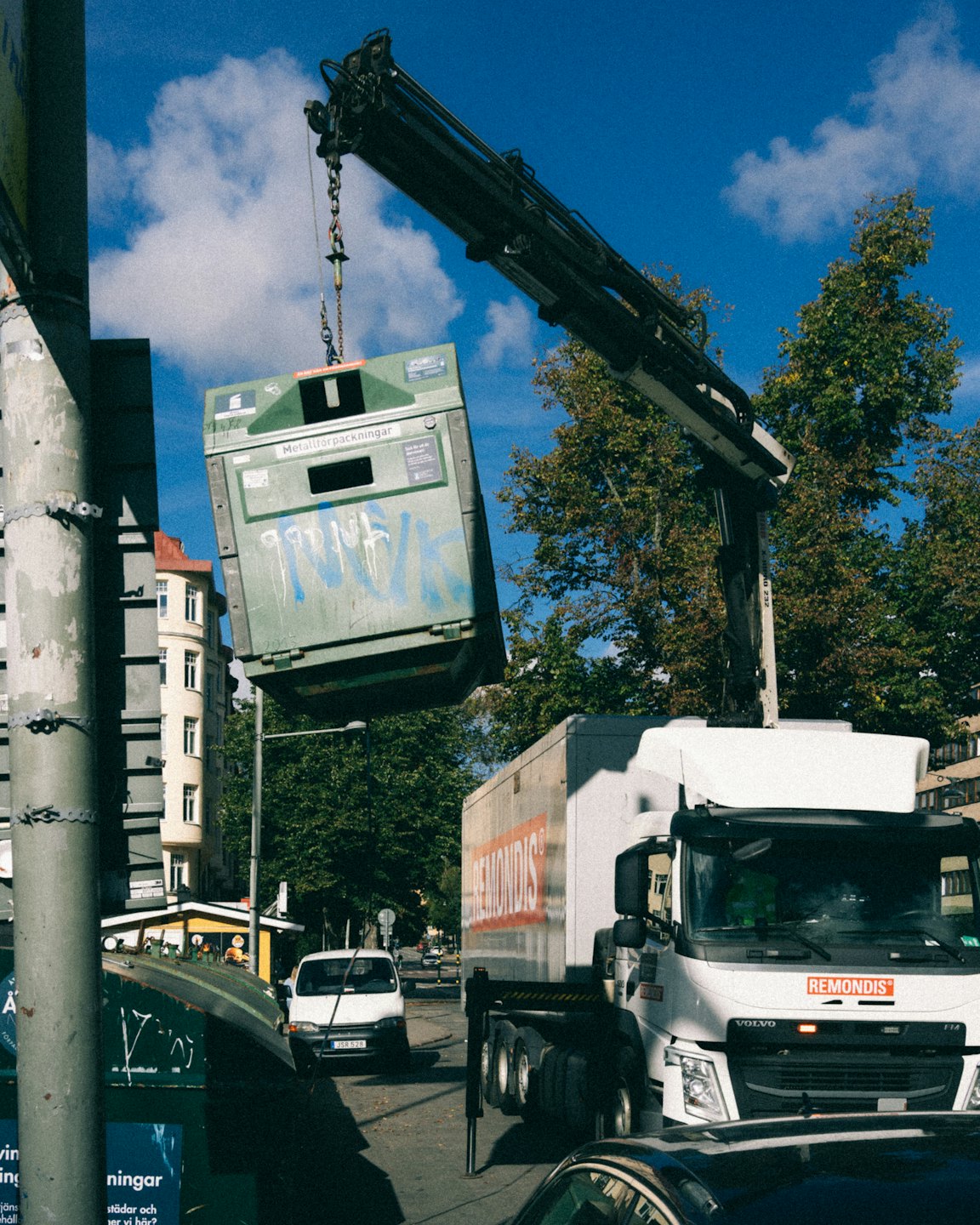 A waste truck lifts a green recycling container in the city.